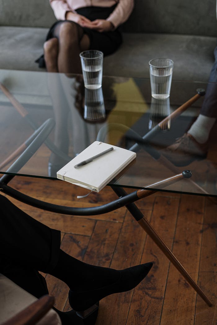 White and Silver Chair Beside Clear Drinking Glass on Glass Table